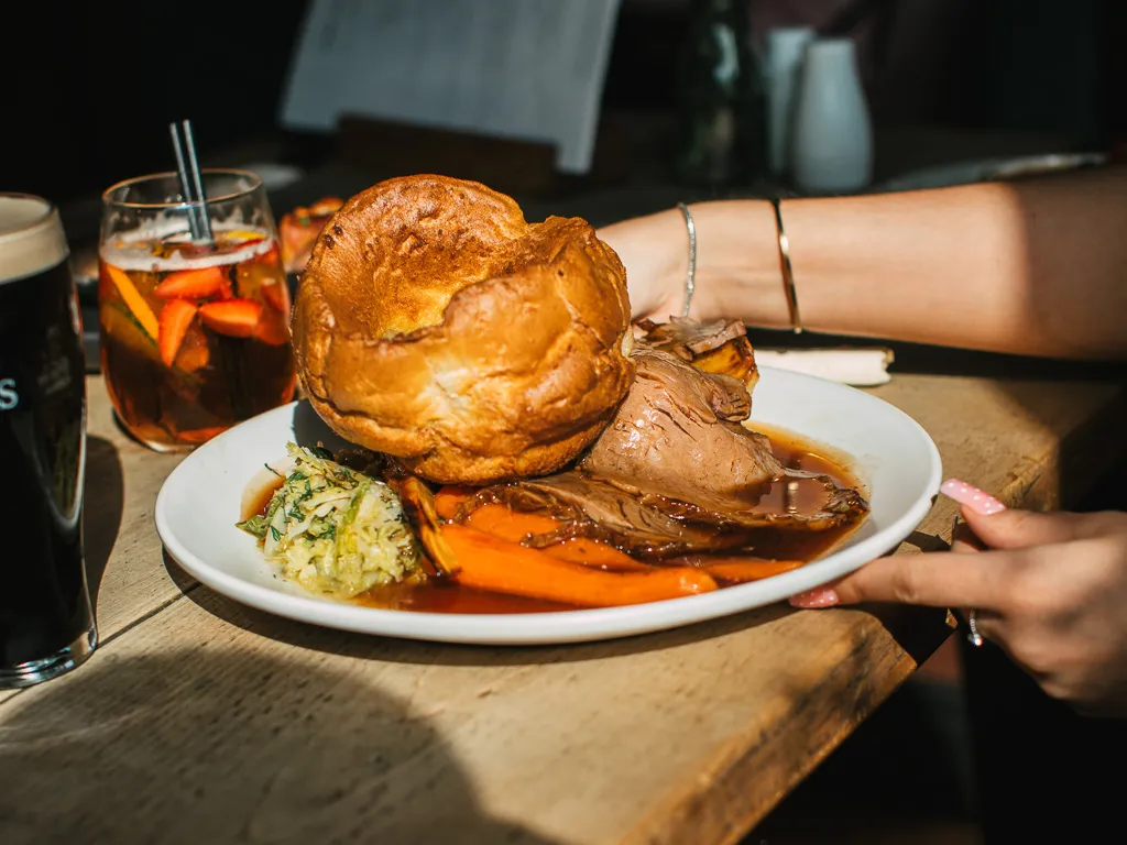 A Sunday roast beef with large Yorkshire pudding on a table in the Barley Mow Hersham along with an Aperol Spritz and a pint of Guinness.
