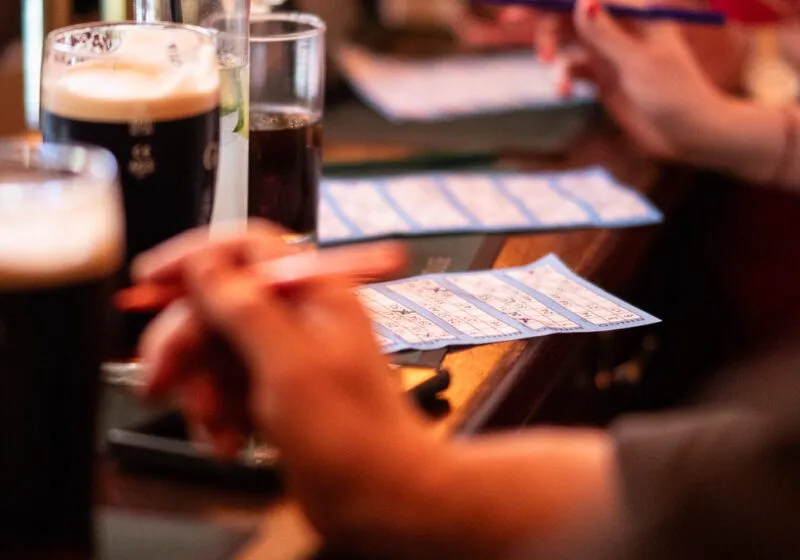 Players with Bingo Cards and Pints of Guinness playing the weekly bingo at The Barley Mow in Hersham.