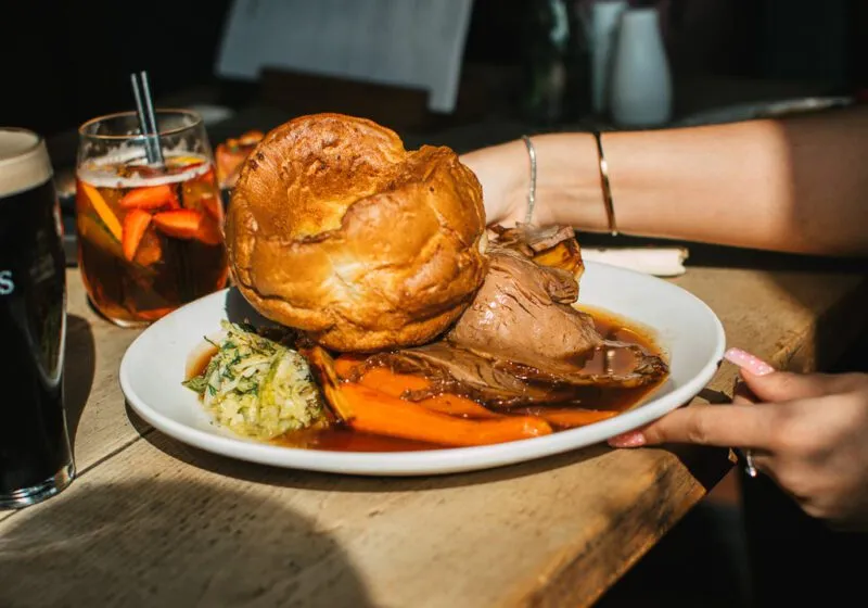 A Sunday roast beef with large Yorkshire pudding on a table in the Barley Mow Hersham along with an Aperol Spritz and a pint of Guinness.